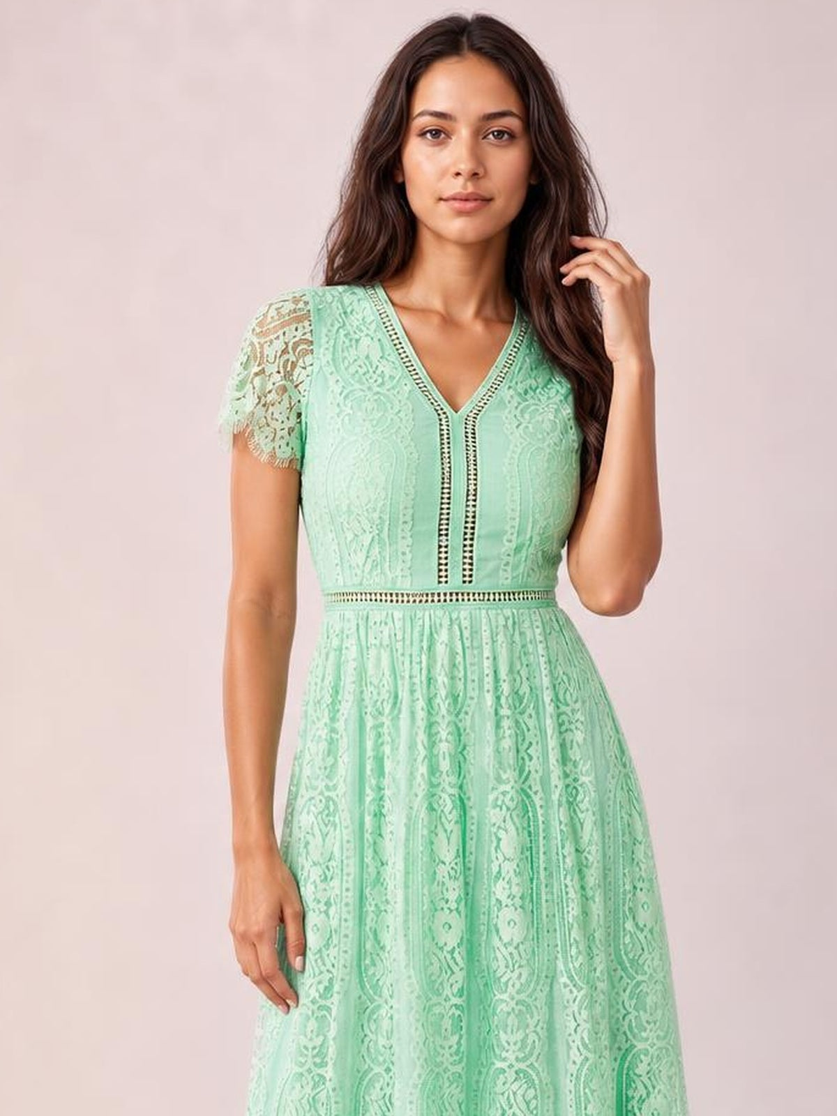 Model poses in a mint green lace maxi dress with a V-neck, scalloped short sleeves, defined waist, vertical trim, and flowing A-line skirt.