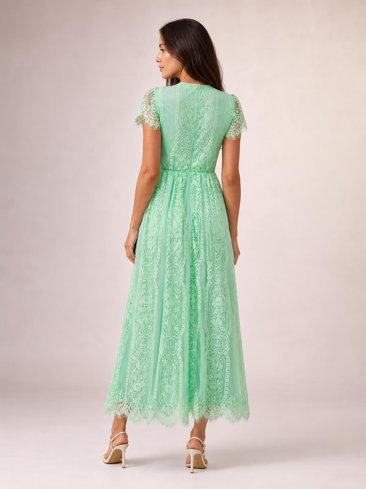 Model shown from behind wears a mint green lace maxi dress with a fitted waist, short scalloped sleeves, a flowing A-line silhouette, and scalloped hem.
