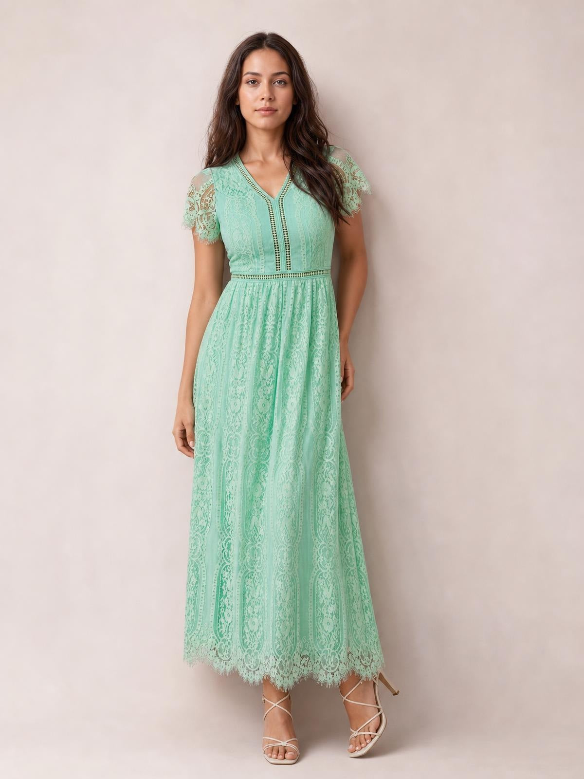 A model stands in a mint green lace maxi dress with a V-neck, short scalloped sleeves, fitted waist, flowing silhouette, and scalloped hem.