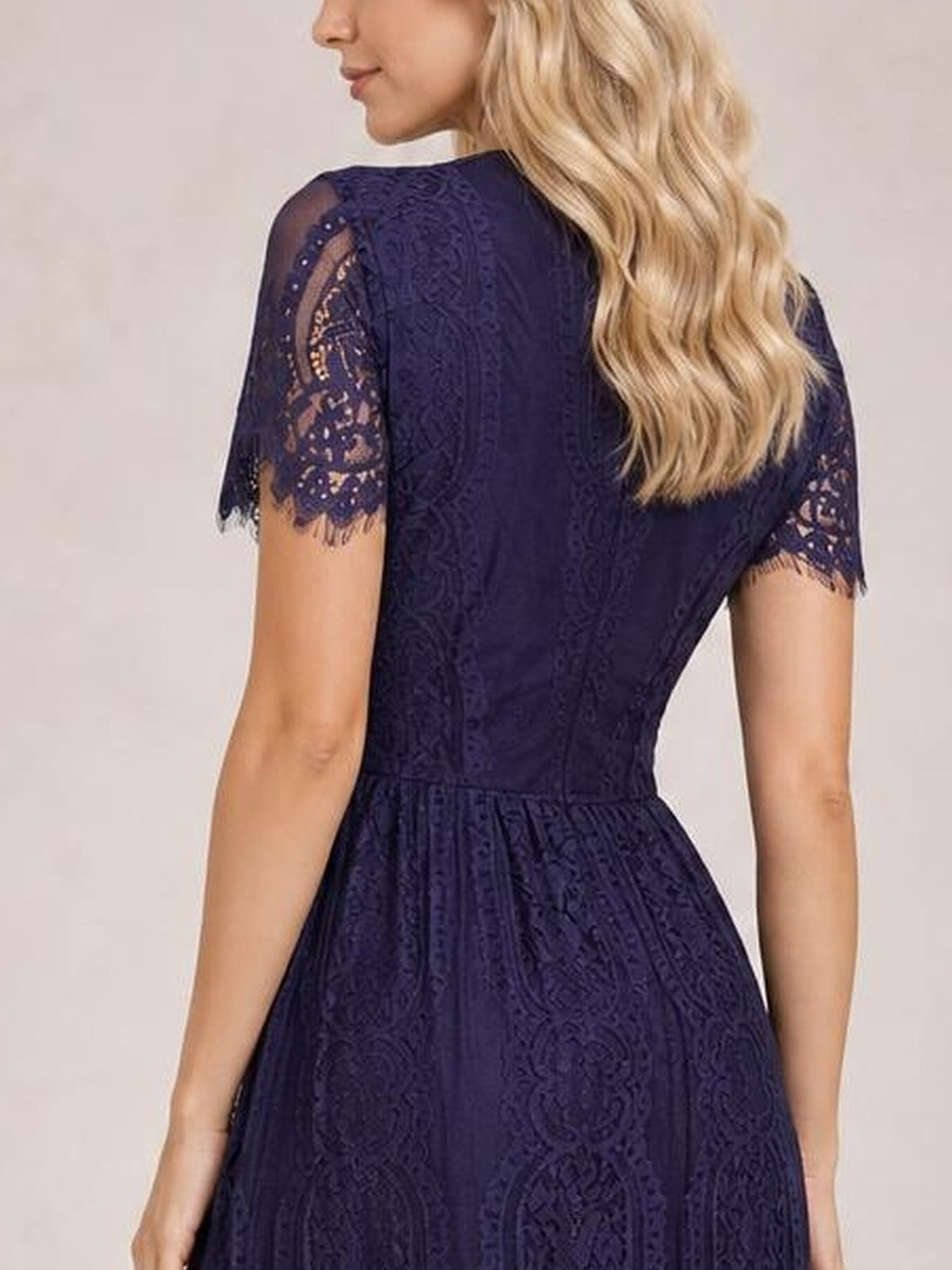 Model shown from behind in a navy lace maxi dress with short scalloped-trim sleeves, a fitted bodice, defined waist, and flowing A-line skirt.