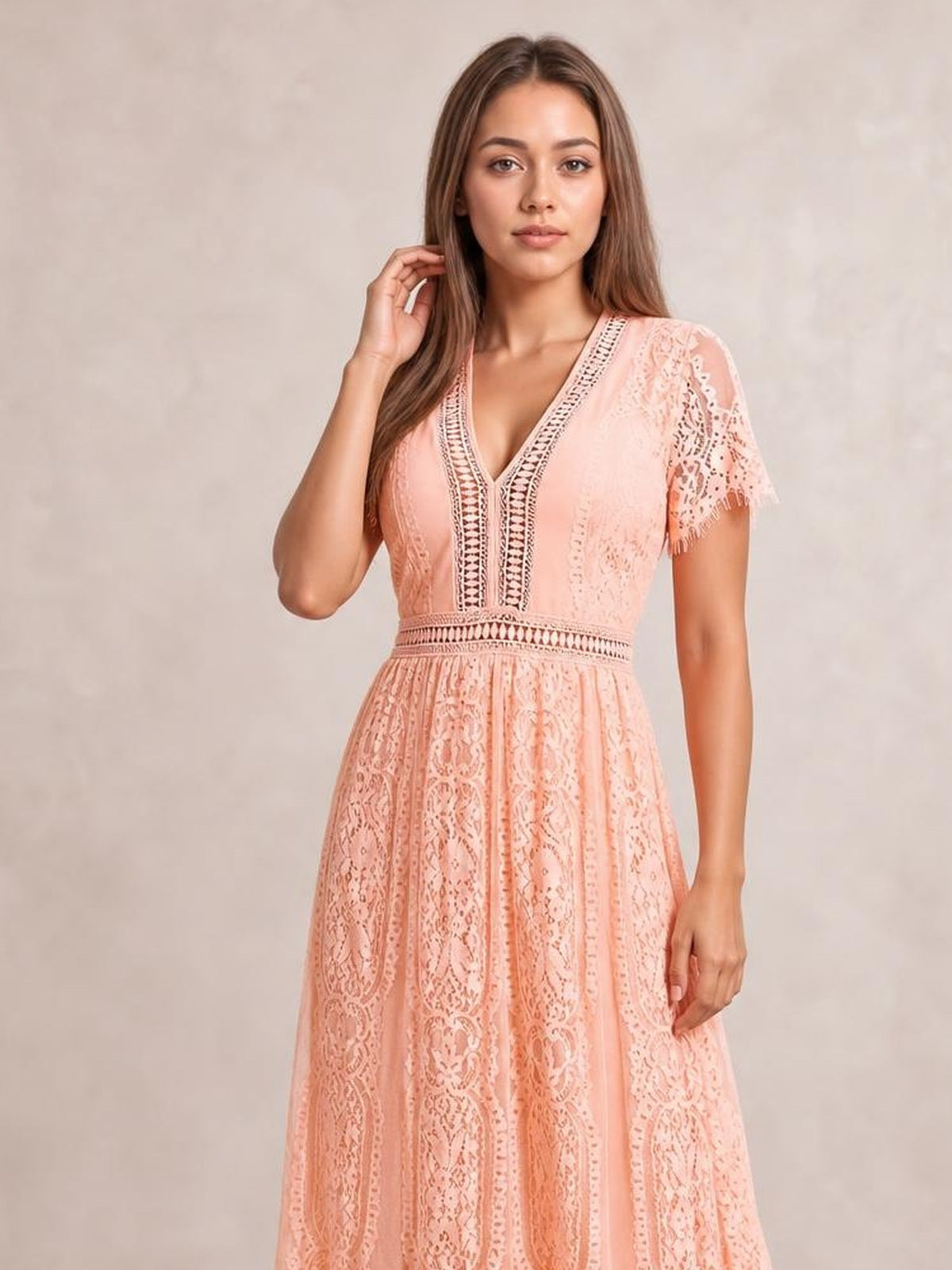 Model poses with one hand in her hair wearing a peach lace plunge maxi dress with scalloped short sleeves, a fitted waist, and flowing A-line silhouette.