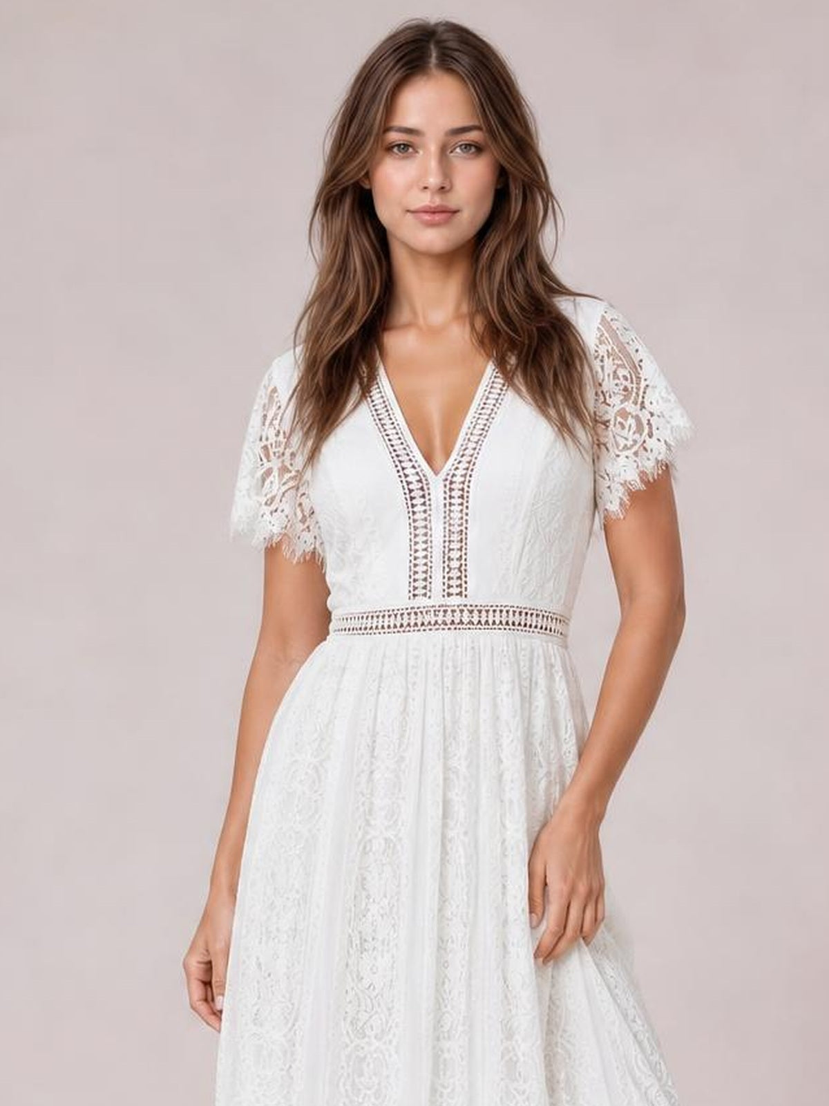 A model stands facing forward in a white lace plunge maxi dress with a V-neck, short scalloped-trim sleeves, defined waist, and flowing silhouette.