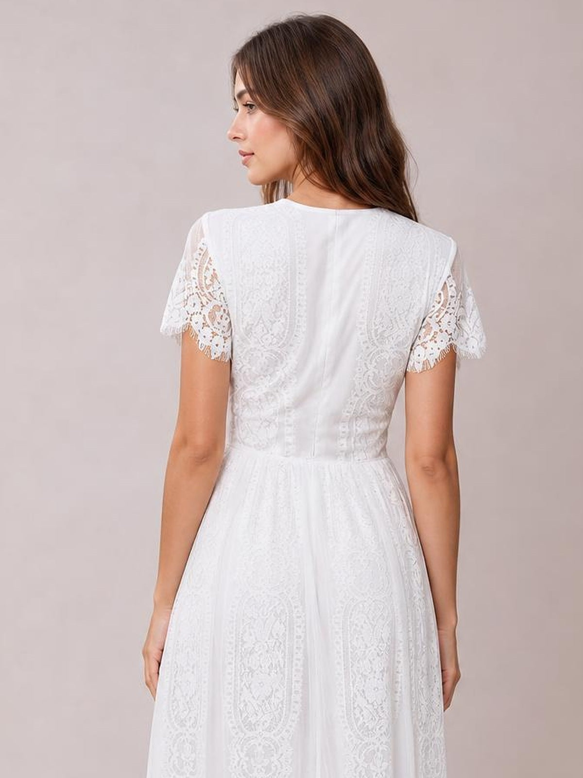 A model poses in a white lace maxi dress with scalloped-trim short sleeves, a fitted waist, and a softly flared silhouette.