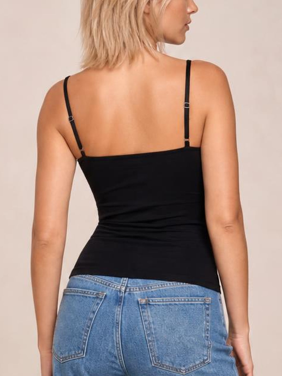 Model shown from the back in a black scoop neck cami with thin adjustable straps and a fitted, smooth silhouette.