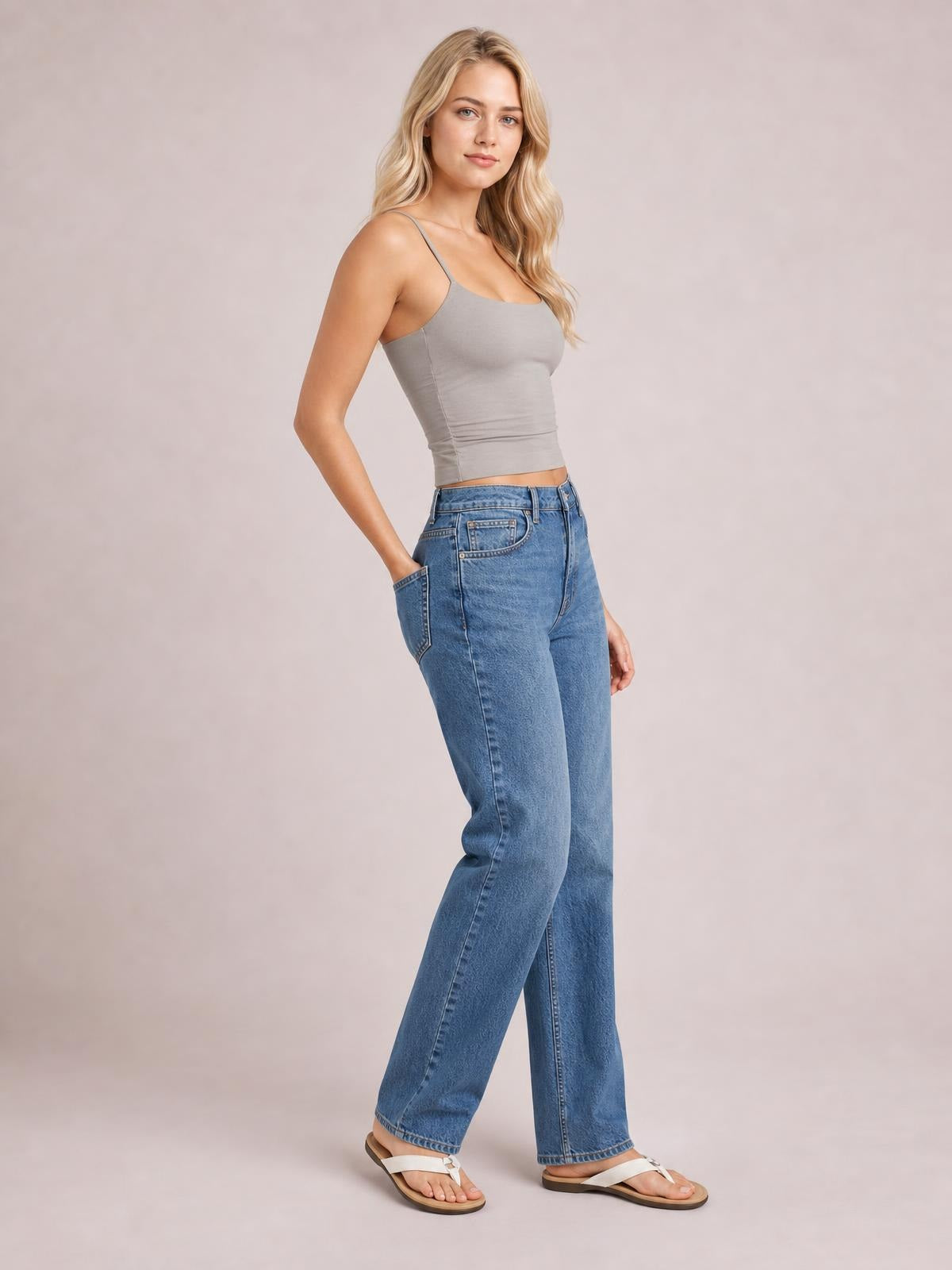 Model wears a gray scoop neck cami with thin straps and a fitted, slightly stretchy silhouette, paired with relaxed blue jeans.