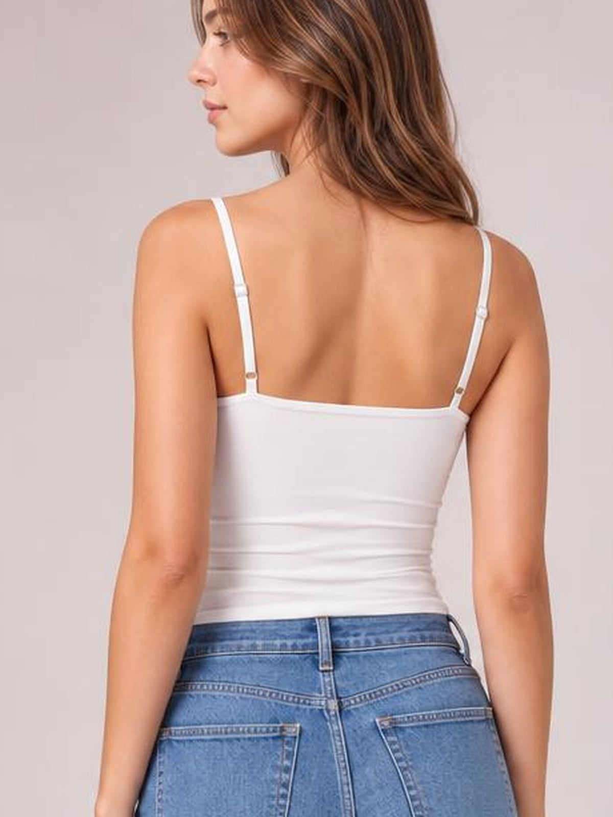 Model shown from the back wearing a white scoop neck cami with thin adjustable straps and a fitted, gently stretchy silhouette.