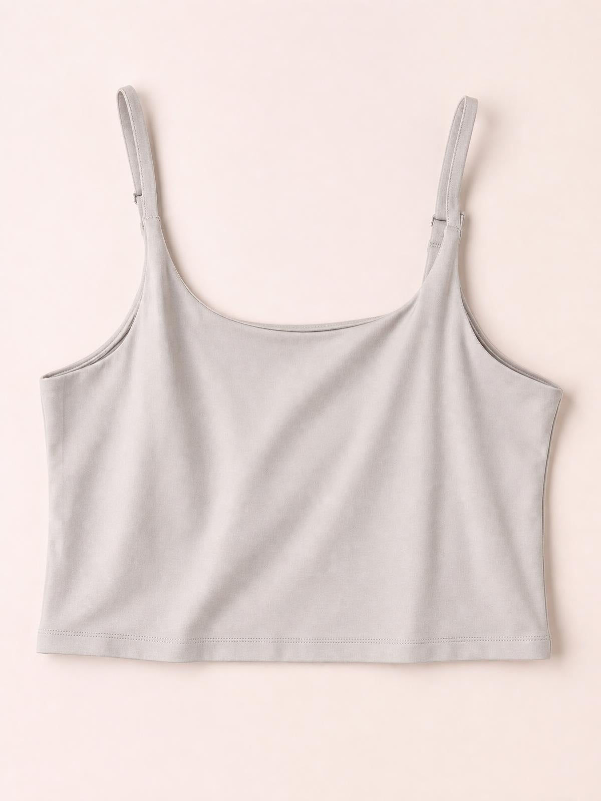Light gray scoop neck cropped cami with slim adjustable straps, a smooth fitted silhouette, opaque fabric, and a neatly stitched straight hem.
