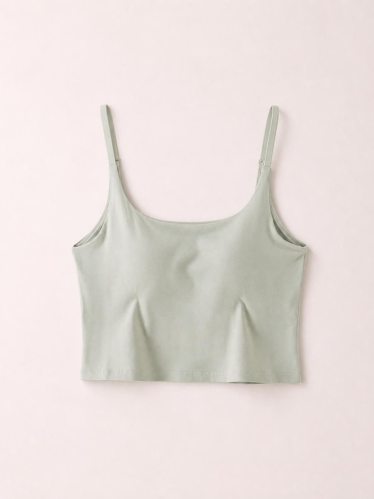 Light sage green cropped cami with a scoop neckline, slim adjustable shoulder straps, fitted silhouette, and clean straight hem.