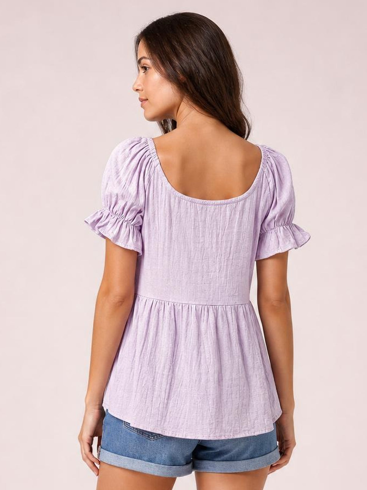 Model shown from the back in a solid lavender blouse with a scoop-square neckline, short gathered flounce sleeves, and a relaxed flared silhouette.