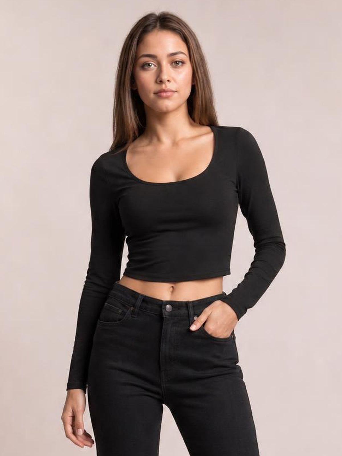 Model wearing a black scoop neck long sleeve cropped T-shirt with a fitted silhouette and straight cropped hem, posed with one hand in her jeans pocket.