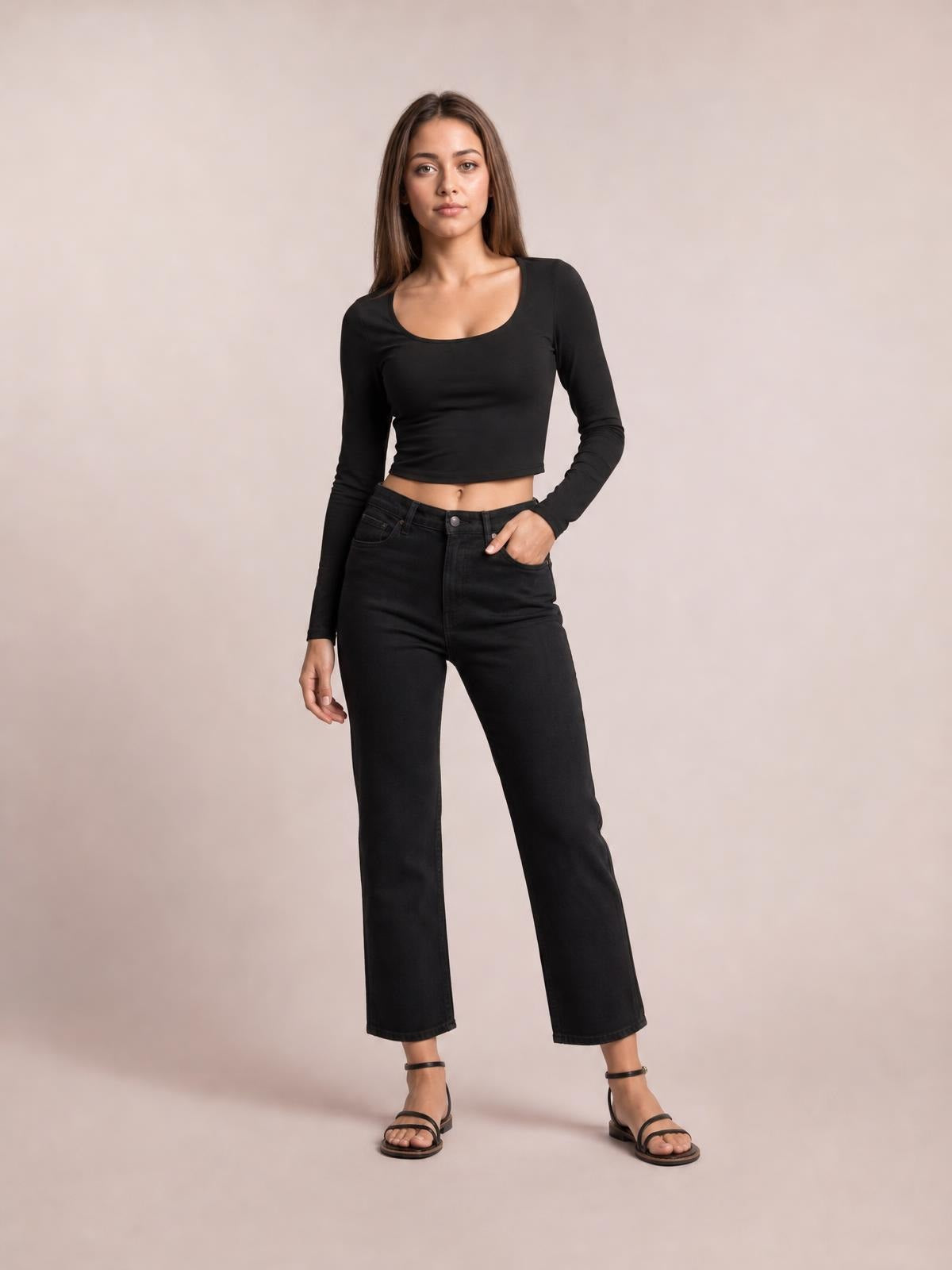 Model poses in a black scoop neck long sleeve cropped T-shirt with a fitted silhouette and straight hem, paired with black jeans.