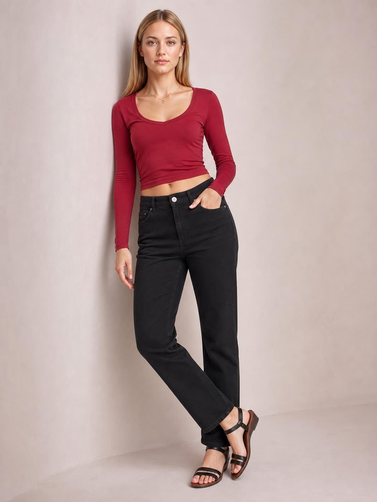 Model poses in a burgundy scoop neck long sleeve cropped T-shirt with a fitted silhouette, layered seams, and a slightly stretchy opaque construction.
