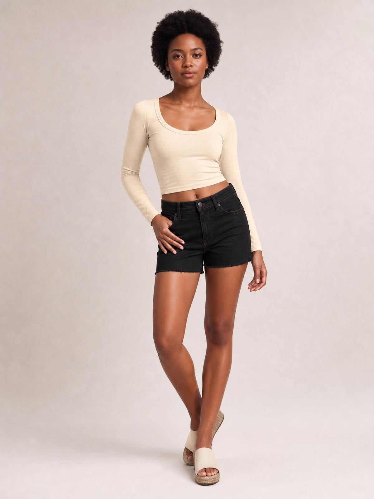 Model poses in a cream scoop neck long sleeve cropped T-shirt with a fitted silhouette and clean basic construction.
