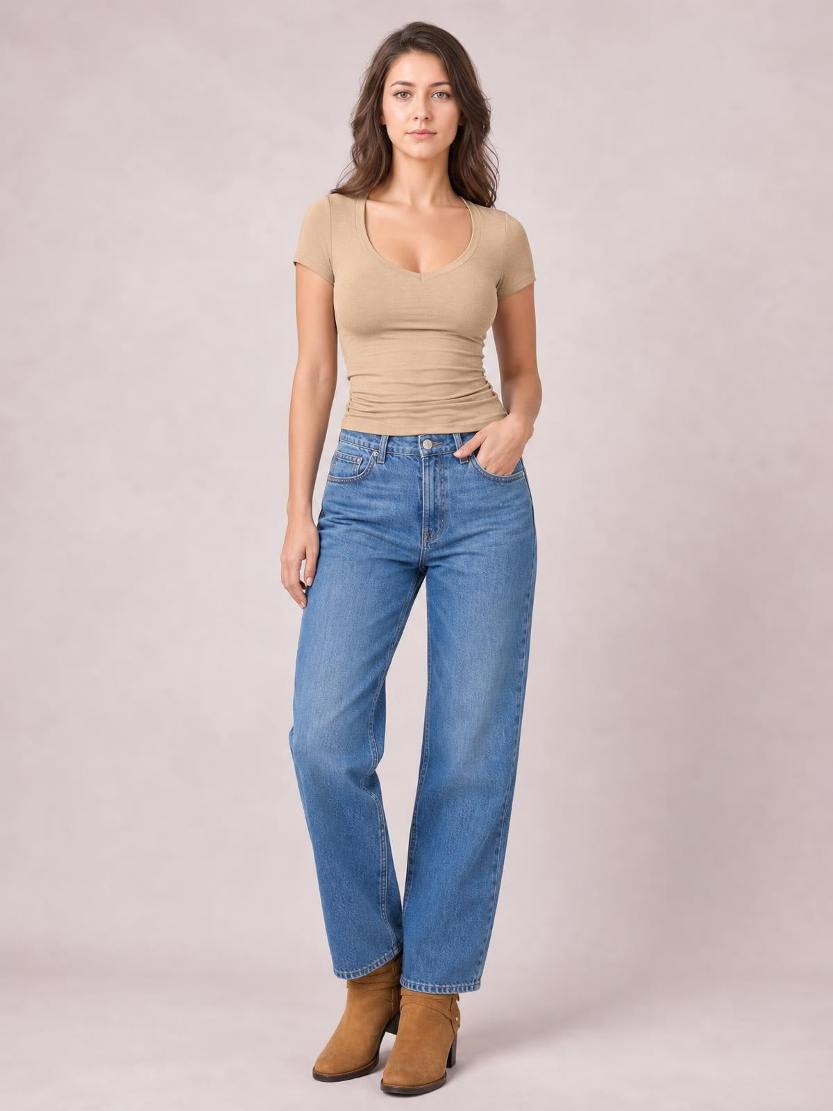 Model wears a tan scoop neck short sleeve T-shirt with a fitted silhouette, smooth opaque construction, and slight waist gathering.