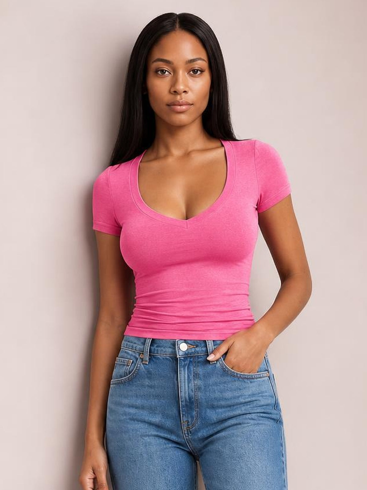 Model wearing a bright pink scoop neck short sleeve T-shirt with a fitted, slightly ruched silhouette and clean double-stitched neckline and sleeve hems.