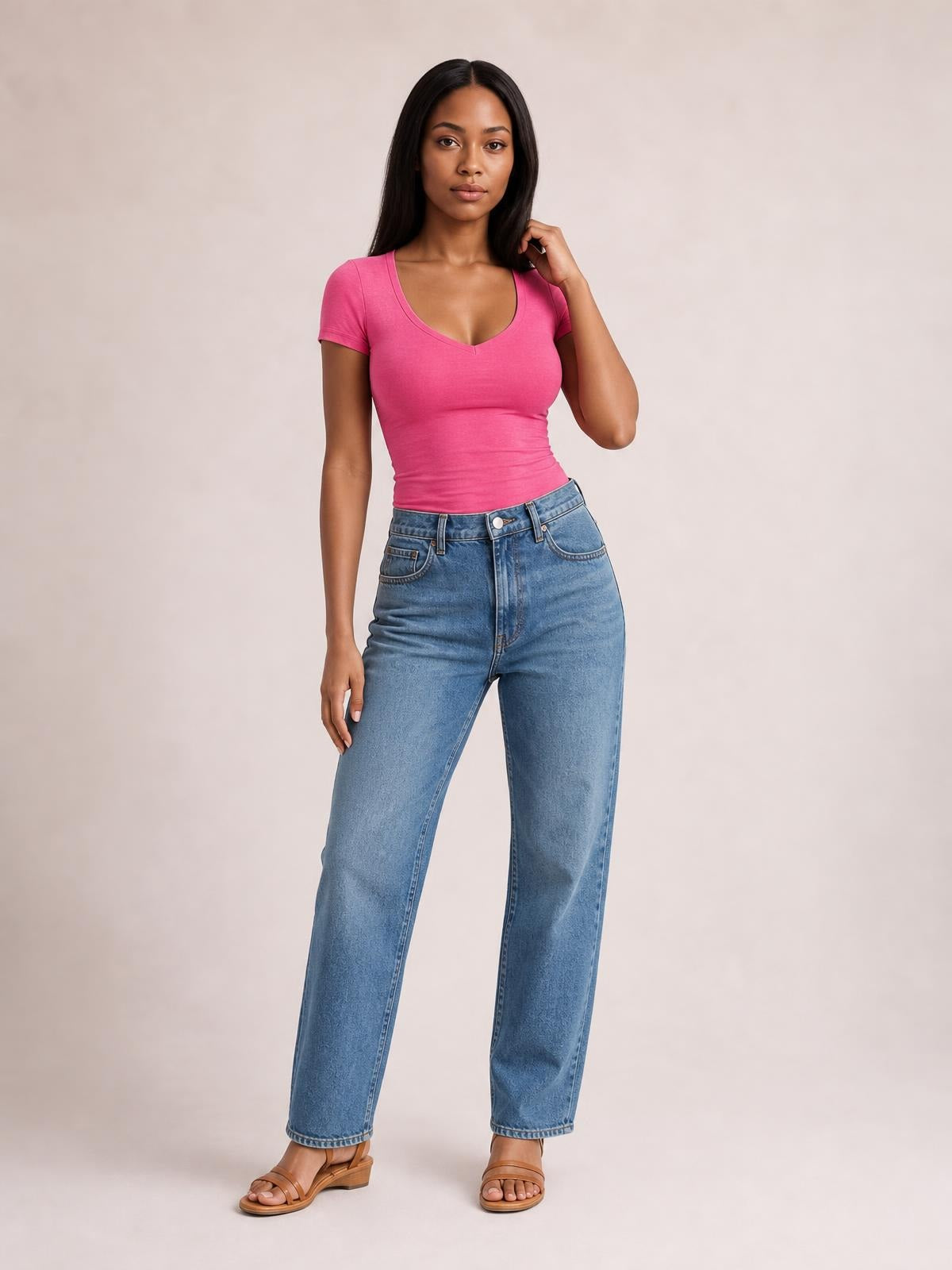 A model poses in a bright pink scoop neck short sleeve T-shirt with a fitted silhouette, curved neckline, and clean sleeve hems, paired with jeans.