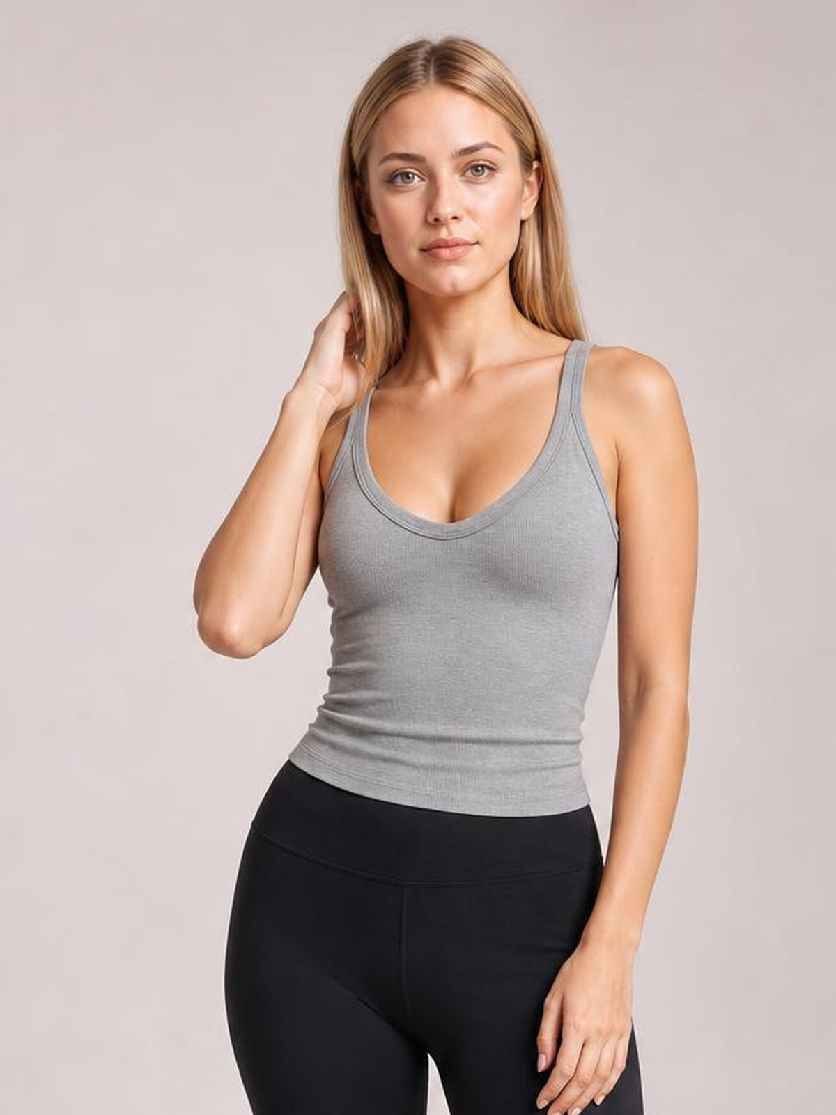Model poses in a fitted gray scoop neck wide strap tank with a smooth, stretchy silhouette and double-stitched neckline trim.