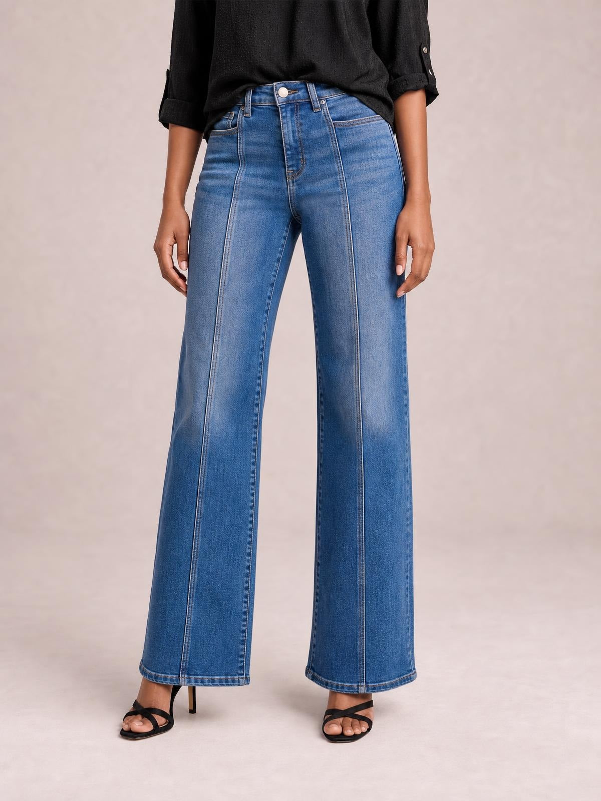 Model wears blue Seam Detail Shift Jeans with a high waist, front pockets, prominent vertical seams, and a relaxed wide-leg silhouette.