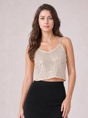 Model wears a champagne sequin cropped cami with a V-neckline, slim spaghetti straps, sleeveless design, and a relaxed straight silhouette.