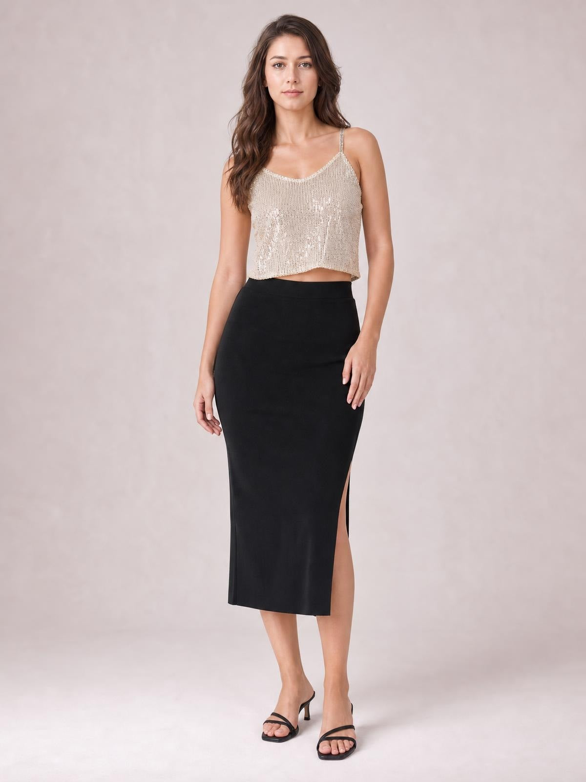 A model stands in a champagne sequin cropped cami with a V-neck, slender spaghetti straps, sleeveless cut, and a straight, slightly relaxed silhouette.