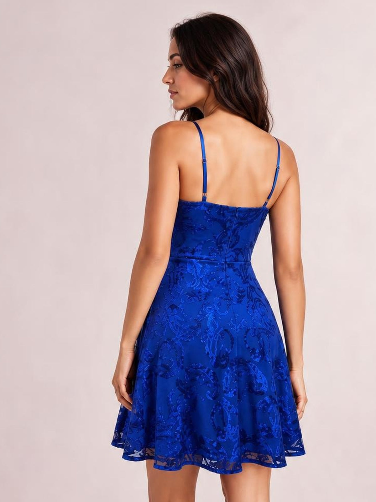 A model poses in a royal blue embellished mini dress with thin adjustable straps, a fitted bodice, defined mid waist, and flared skirt.