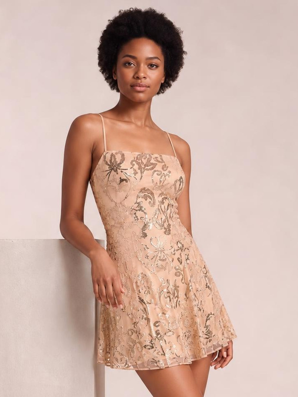 Model wears a blush sequin embellished mini dress with thin straps, square neckline, fitted mid-waist bodice, and flared A-line skirt.