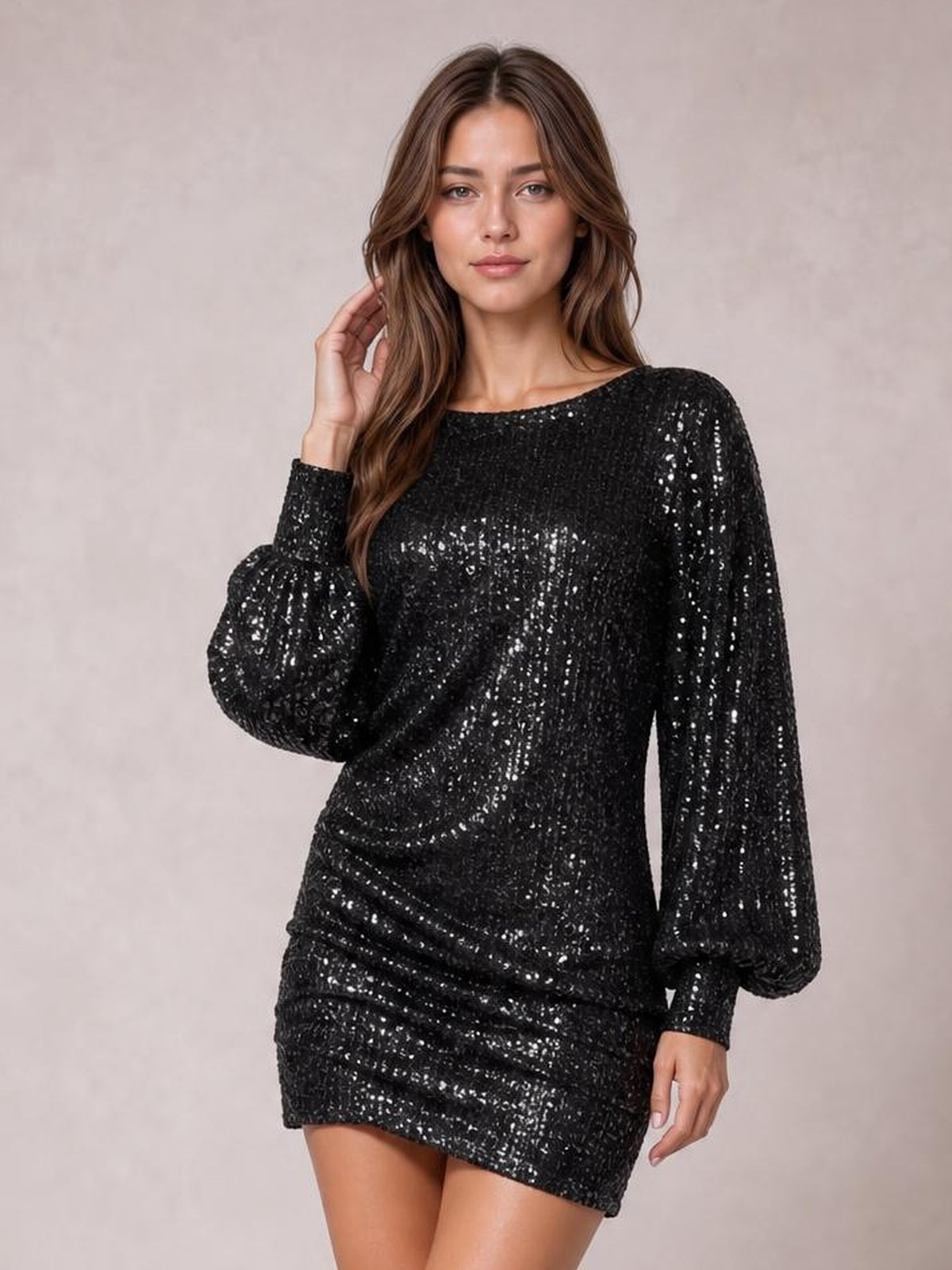 A model poses in a black sequin mini dress with a wide neckline, long voluminous sleeves, a fitted silhouette, and ruched detailing across the skirt.