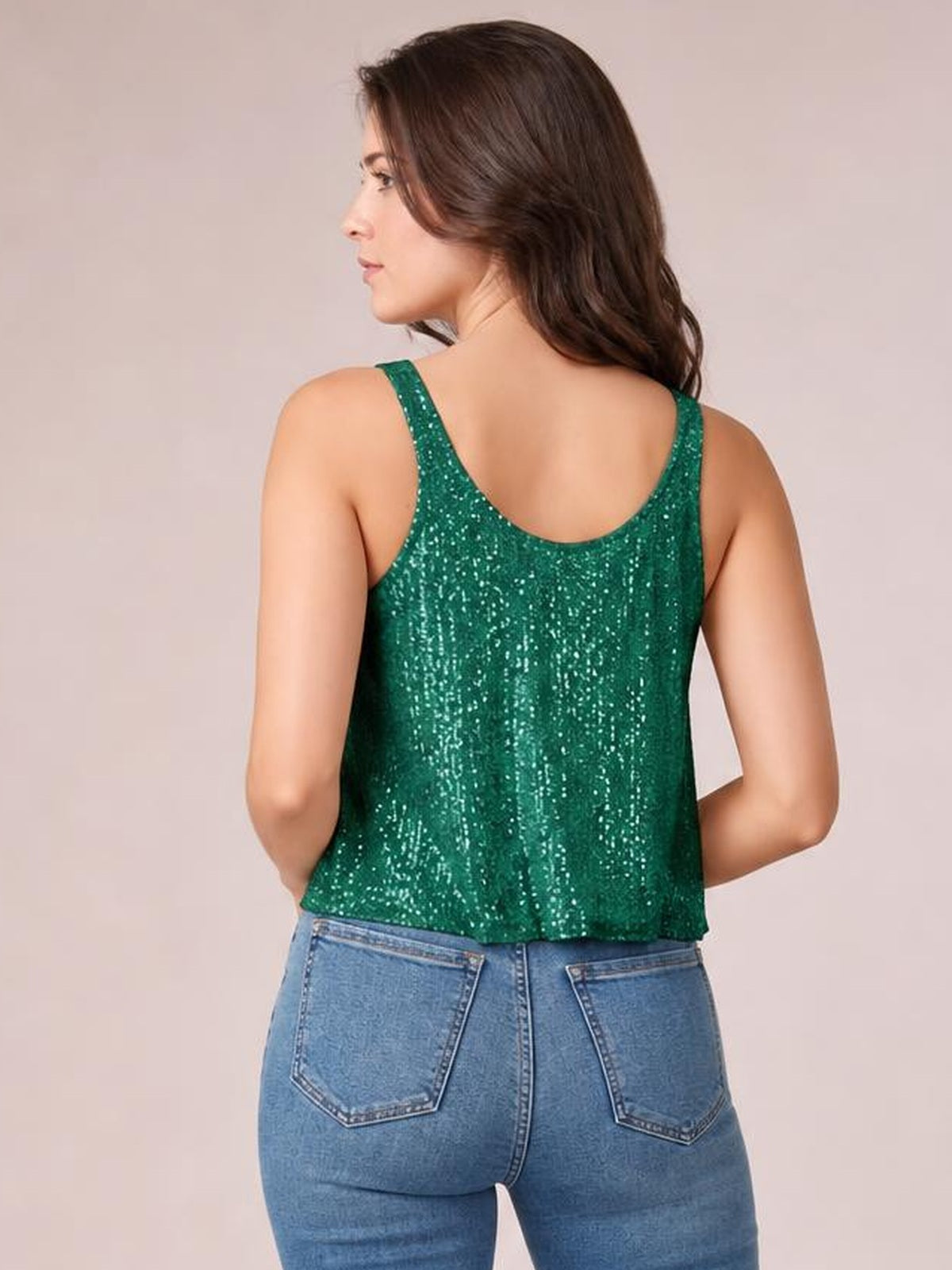 Model turns slightly to show the green sequin scoop neck tank’s back, featuring wide shoulder straps, a relaxed straight silhouette, and shimmering construction.