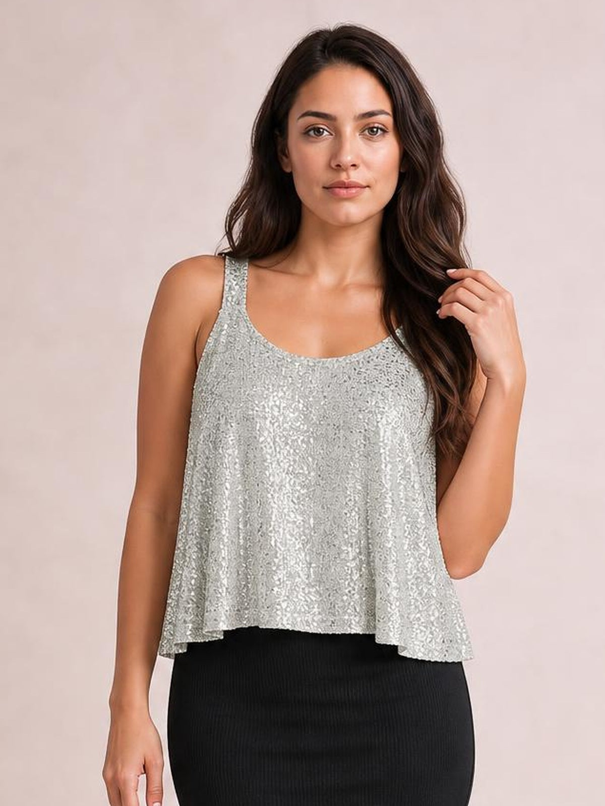 Model wearing a silver sequin scoop neck tank with wide straps and a loose, slightly flared silhouette, gently touching her hair.