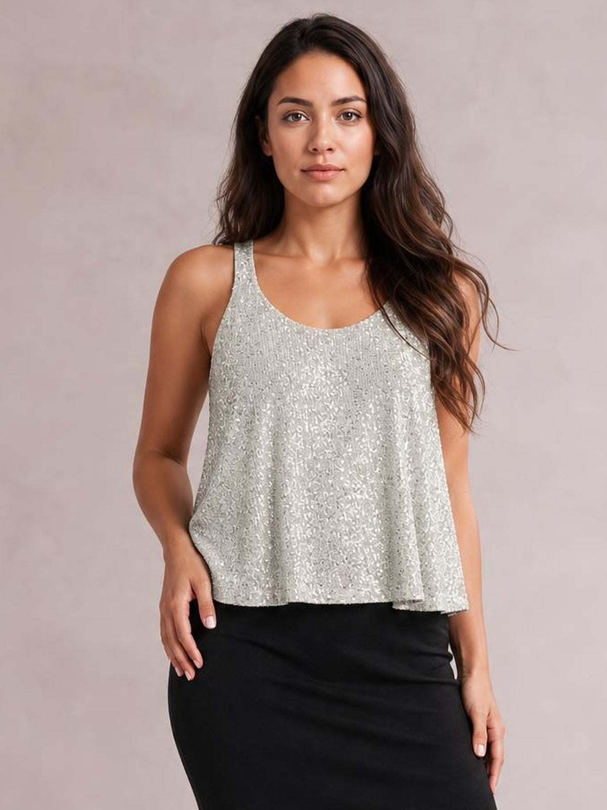 Model wearing a silver sequin scoop neck tank with wide shoulder straps and a loose, slightly flared silhouette, standing with one hand at her hip.