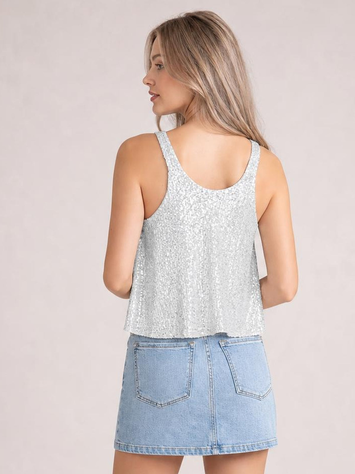 Model viewed from the back wearing a silver sequin scoop neck tank with wide shoulder straps, a relaxed cropped silhouette, and a straight hem.