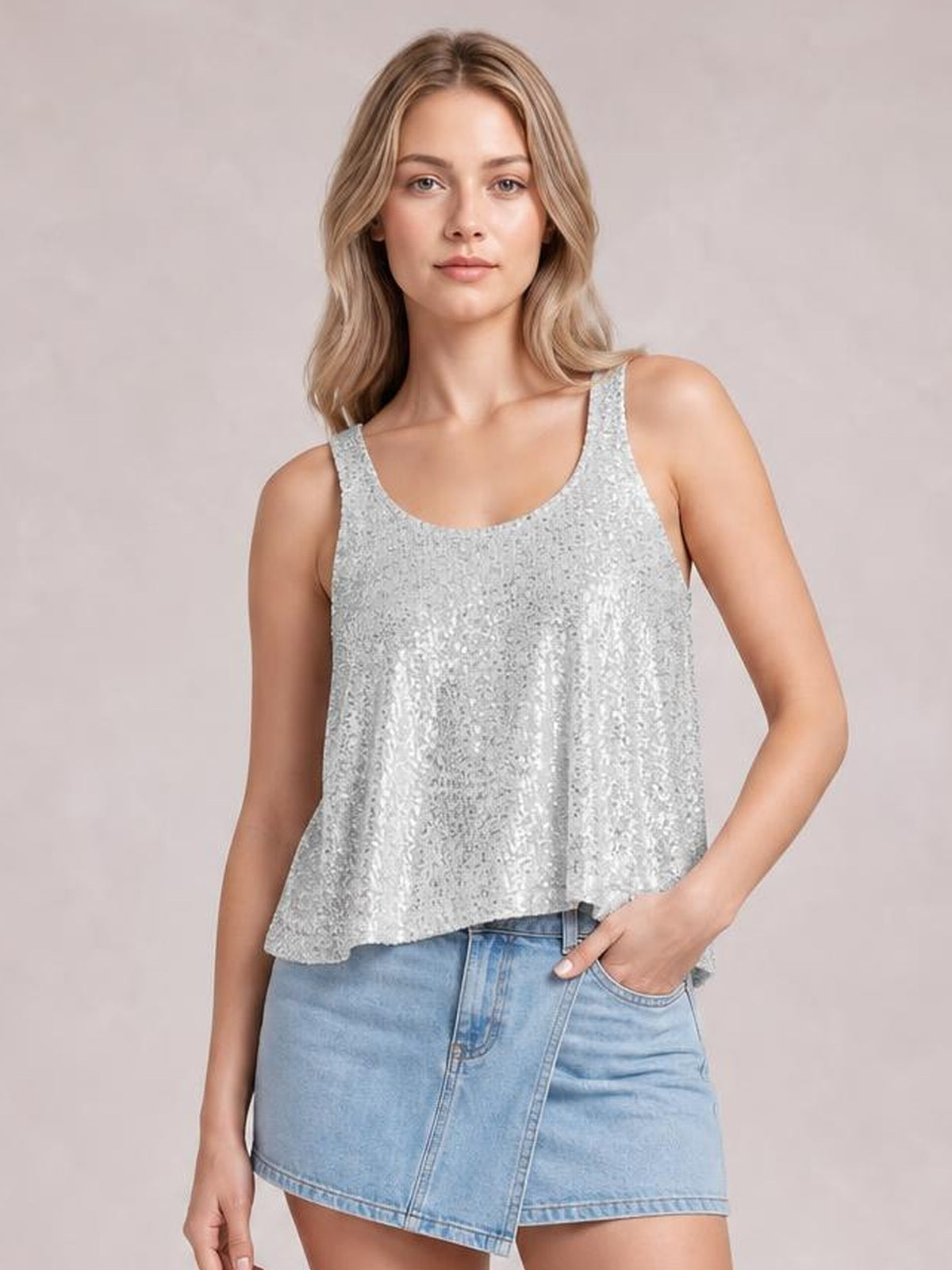 Model poses with one hand in her pocket, wearing a shimmering silver sequin scoop neck tank with wide straps and a relaxed, slightly flared silhouette.