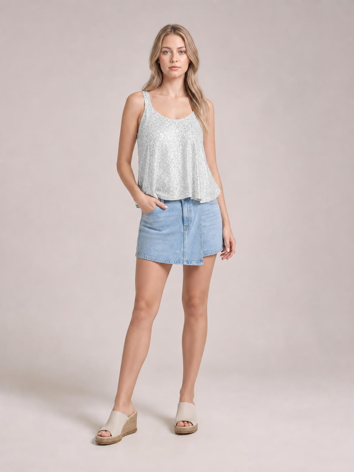 Model poses in a shimmering silver sequin scoop neck tank with wide straps and a relaxed, slightly flared silhouette.