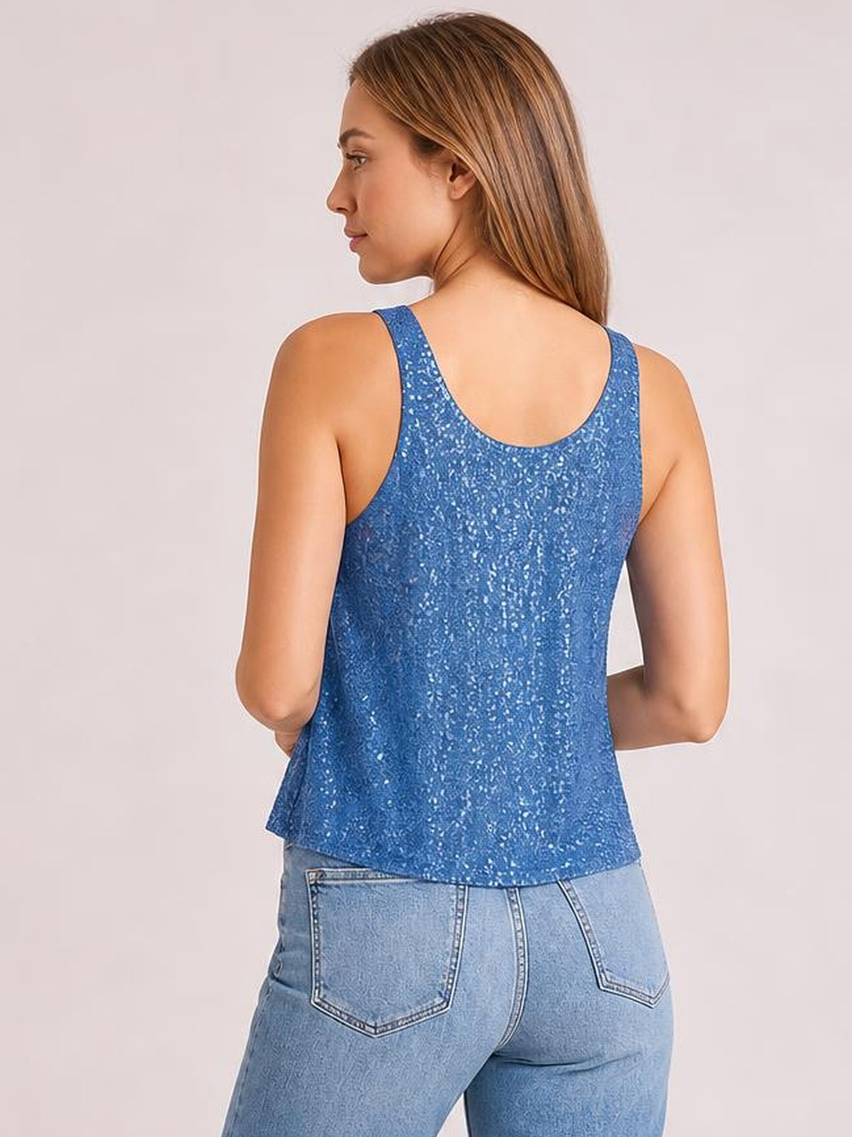 A model poses turned away in a blue sequin tank with a scoop neckline, wide shoulder straps, and a relaxed, straight silhouette.