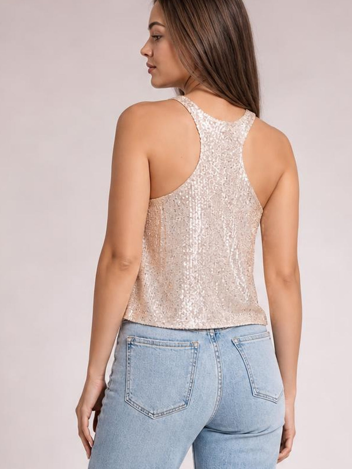 Model shown from behind wearing a shimmery champagne sequin tank with a racerback design, wide shoulder straps, and a relaxed straight silhouette.