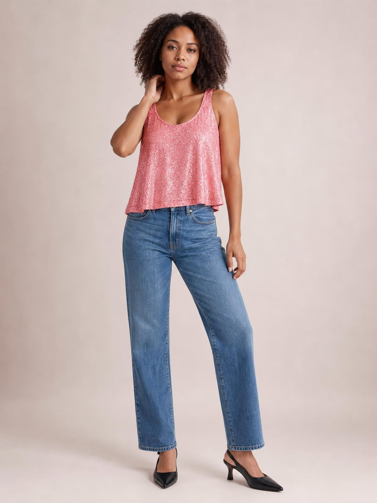 A model poses in a pink sequin scoop neck tank with wide shoulder straps, sleeveless construction, and a softly loose, flowing silhouette.