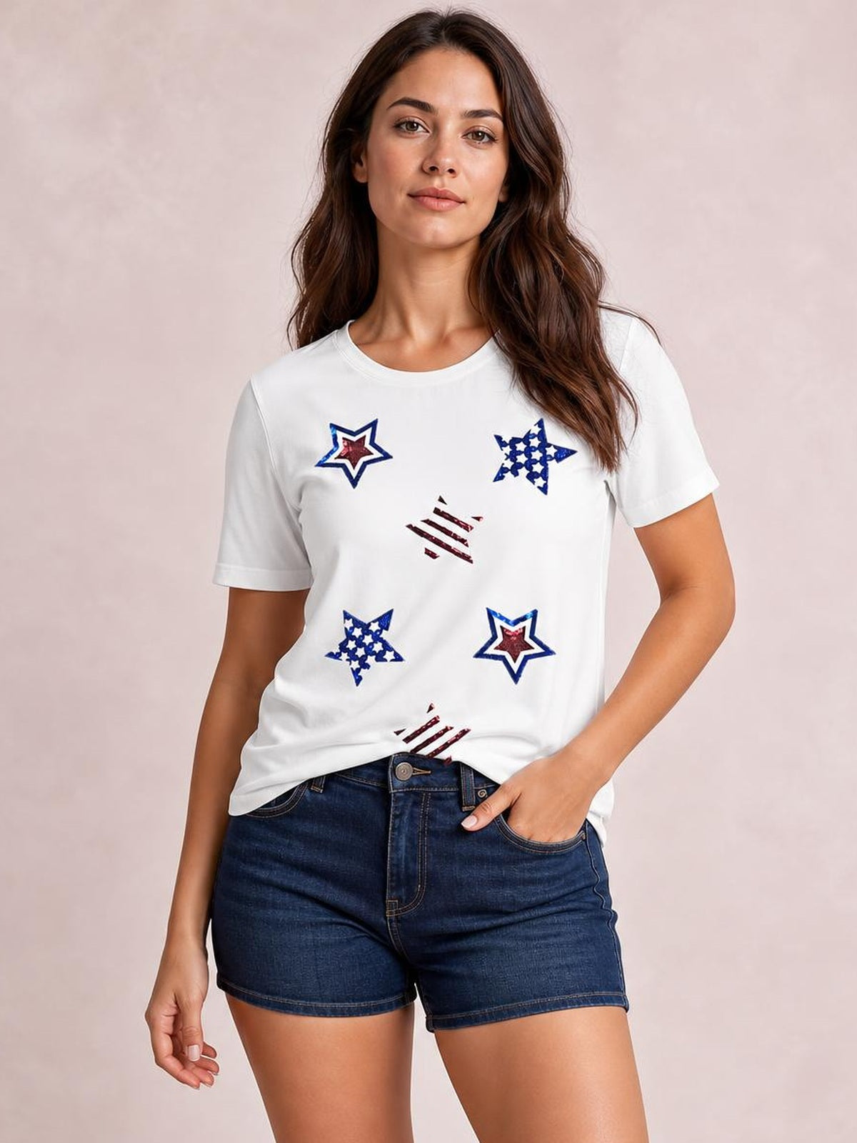 Model poses in a white round-neck short-sleeve T-shirt with colorful sequin star designs and a relaxed straight silhouette.