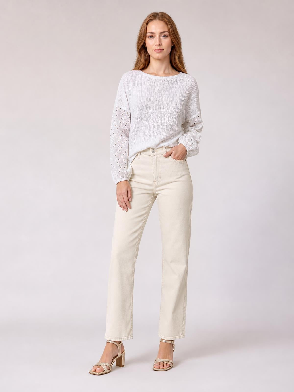 A model stands in a relaxed pose wearing a white eyelet blouse with a round neck, dropped shoulders, textured body, and openwork long sleeves.