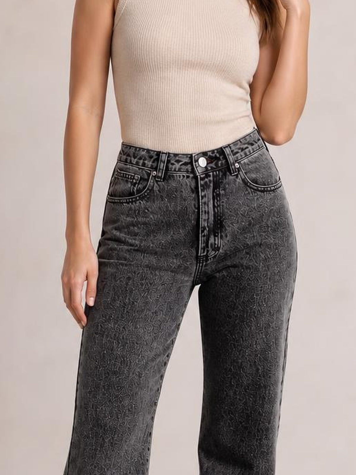 A model wears dark gray high-waisted jeans with front pockets, belt loops, contrast stitching, a button fly, and a relaxed straight-leg silhouette.