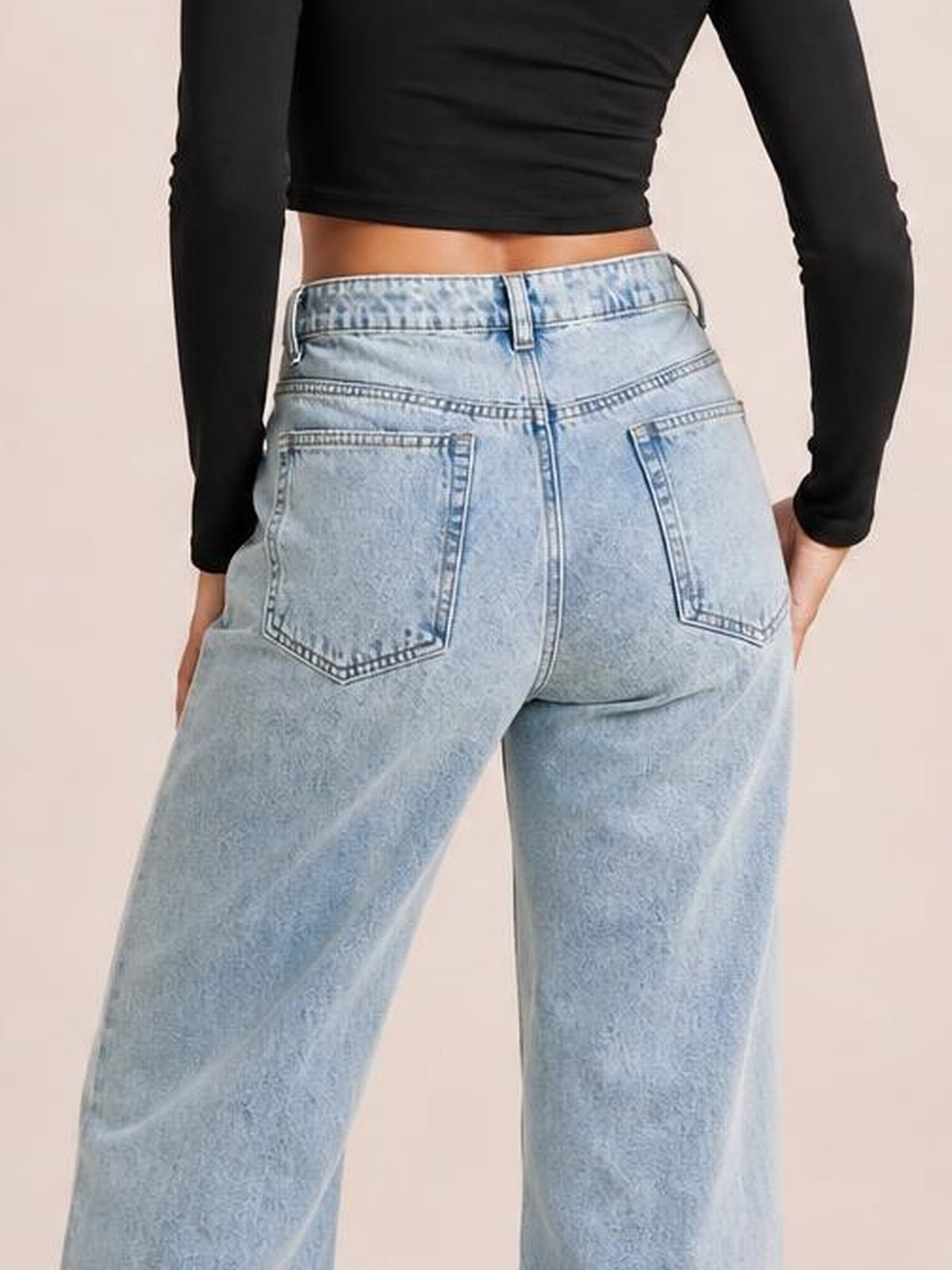 A model is shown from behind wearing light blue jeans with a high waist, belt loops, contrast stitching, and two large back pockets in a relaxed straight-leg silhouette.