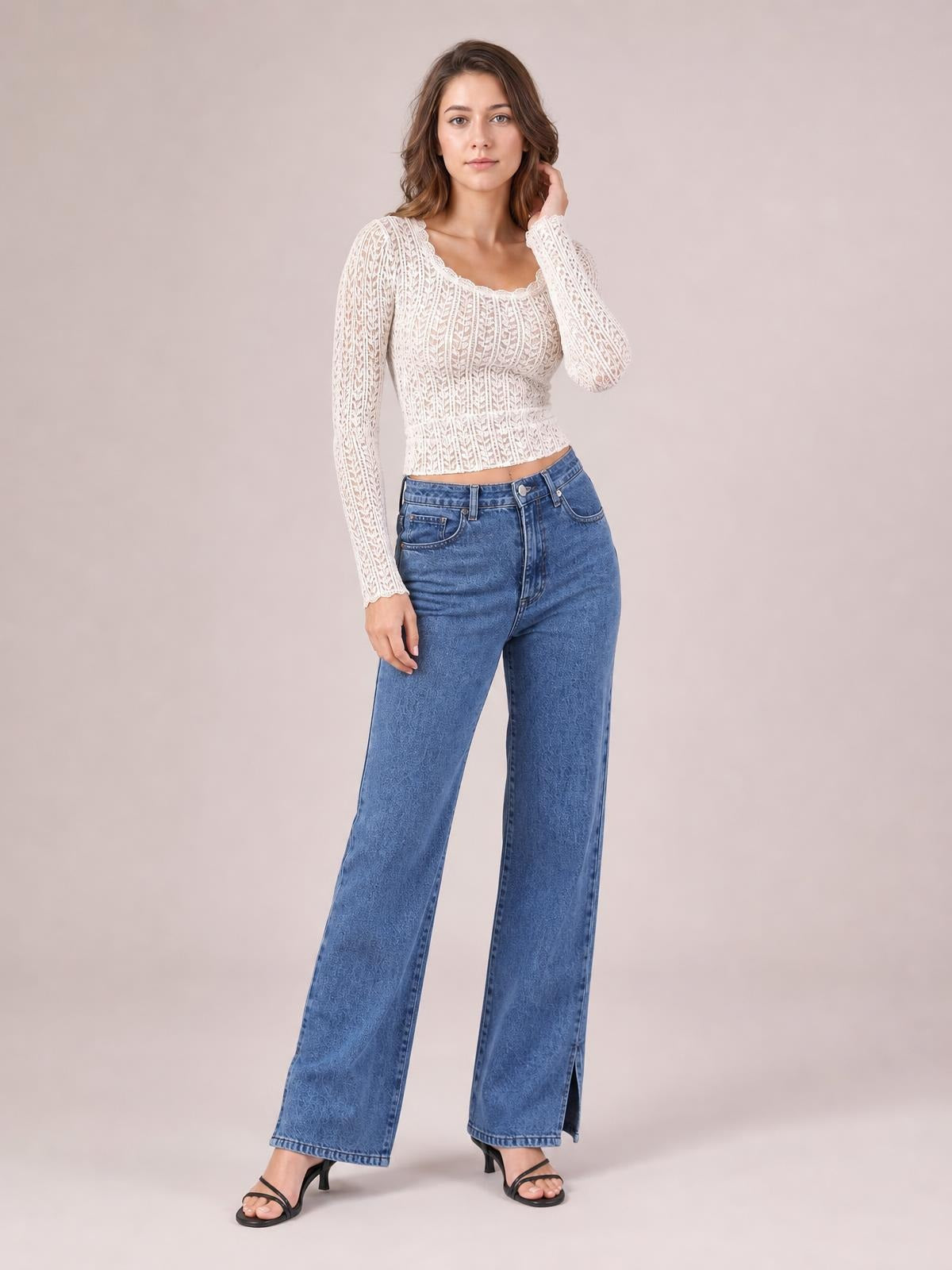A model poses in blue side slit jeans with front pockets, belt loops, a high waist, and a wide-leg silhouette with hem openings.
