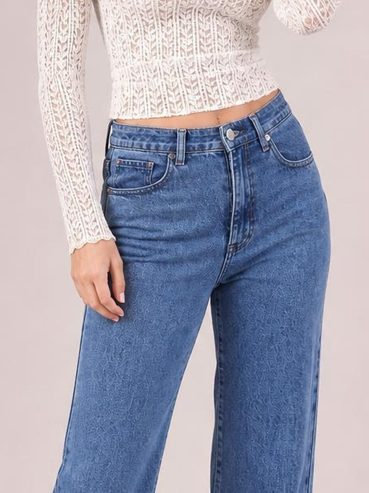Model wears blue jeans with a structured waistband, belt loops, button closure, front pockets, and a relaxed straight-leg silhouette.