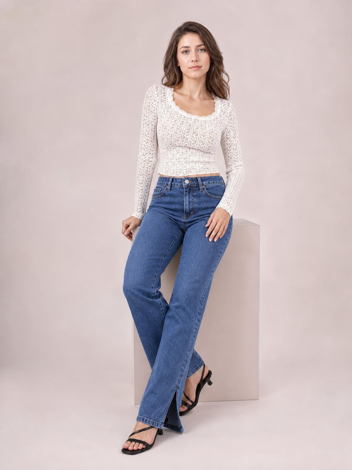 A model wears blue side slit jeans with front pockets, a high waist, and a relaxed straight-leg silhouette while seated with crossed legs.