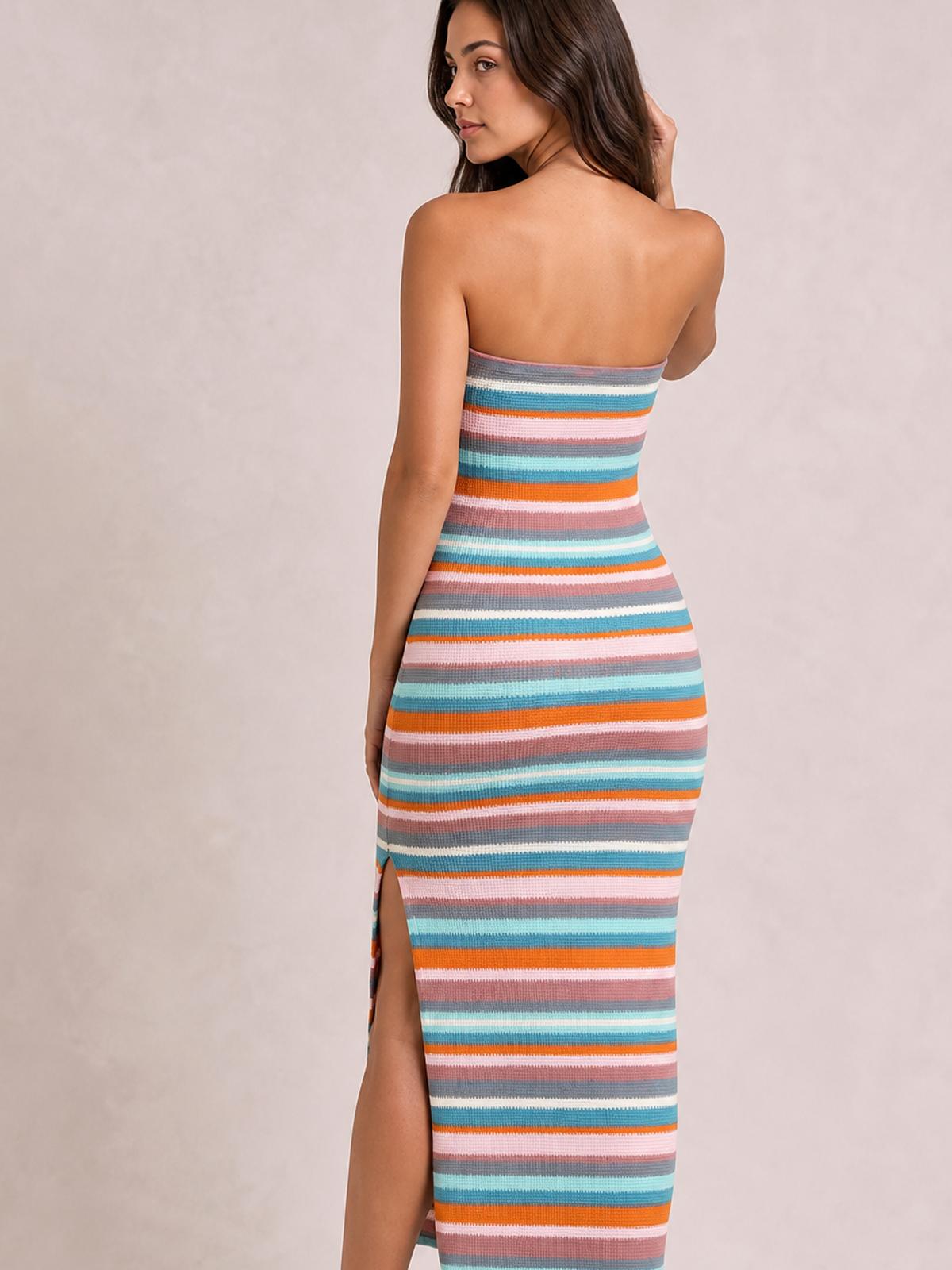 A model poses in a long, body-skimming blue striped tube dress with a strapless neckline, colorful horizontal stripes, and a side slit revealing the leg.