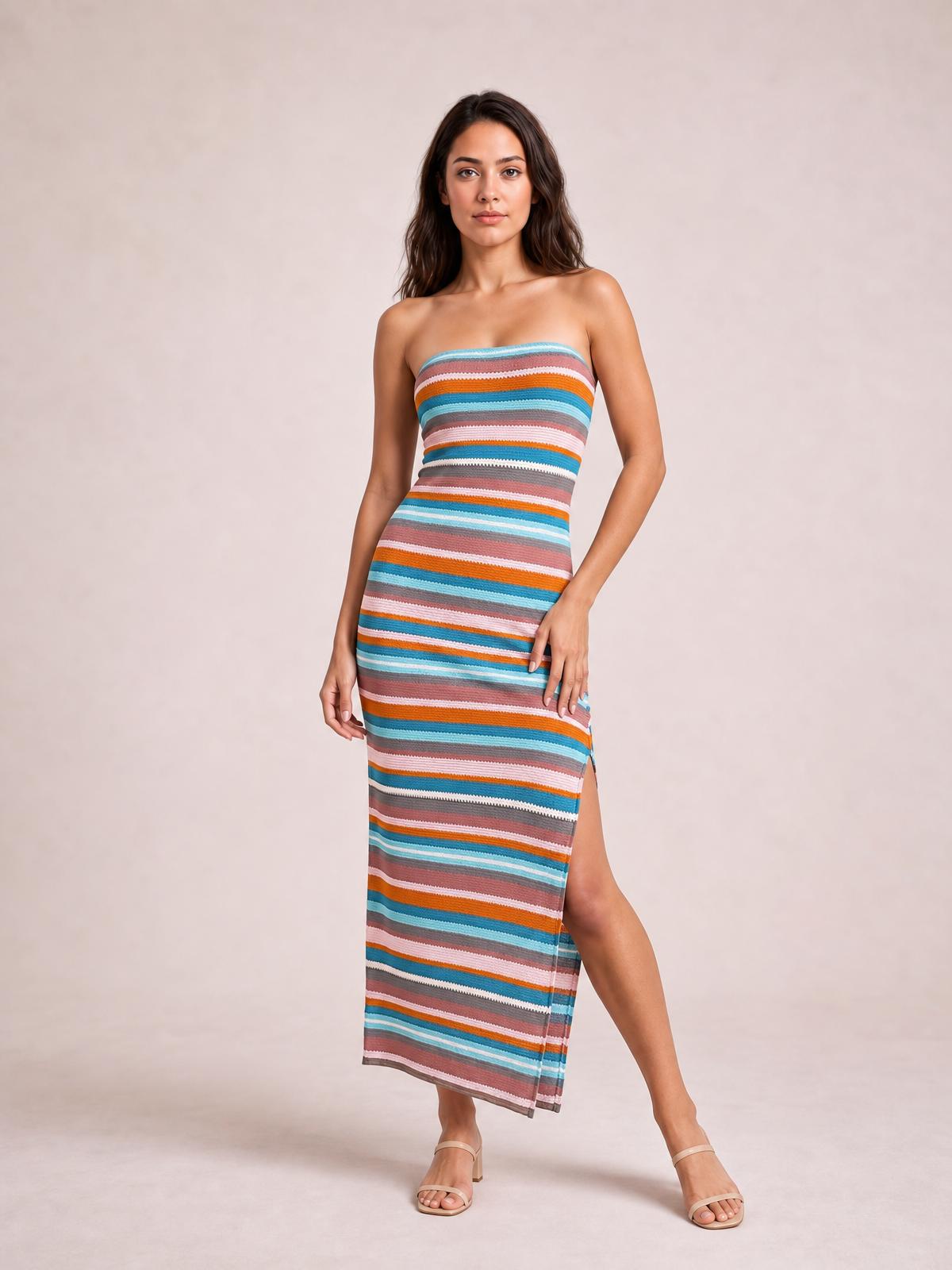 Model poses in a colorful blue striped tube dress with a strapless neckline, body-skimming silhouette, long length, and side slit.