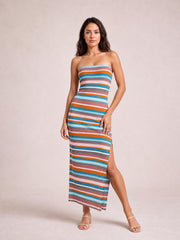 Model poses in a colorful blue striped tube dress with a strapless neckline, body-skimming silhouette, long length, and side slit.