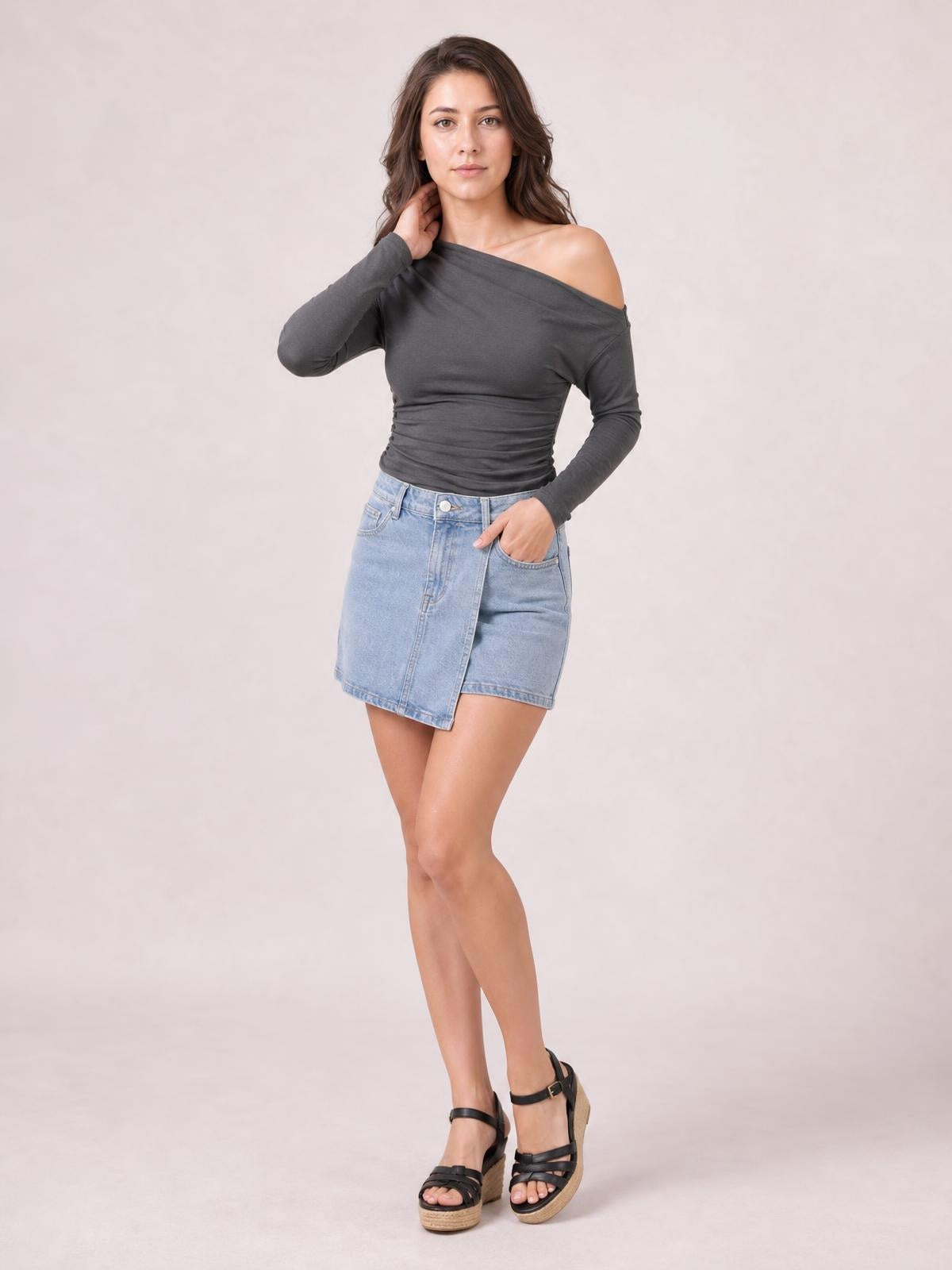 Model poses in a charcoal gray single-shoulder long-sleeve T-shirt with a ruched fitted silhouette and exposed shoulder.