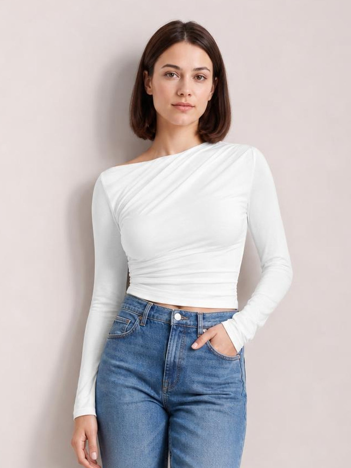 Model wearing a white single-shoulder long-sleeve T-shirt with a fitted silhouette, diagonal draping, ruched waist, and one exposed shoulder.