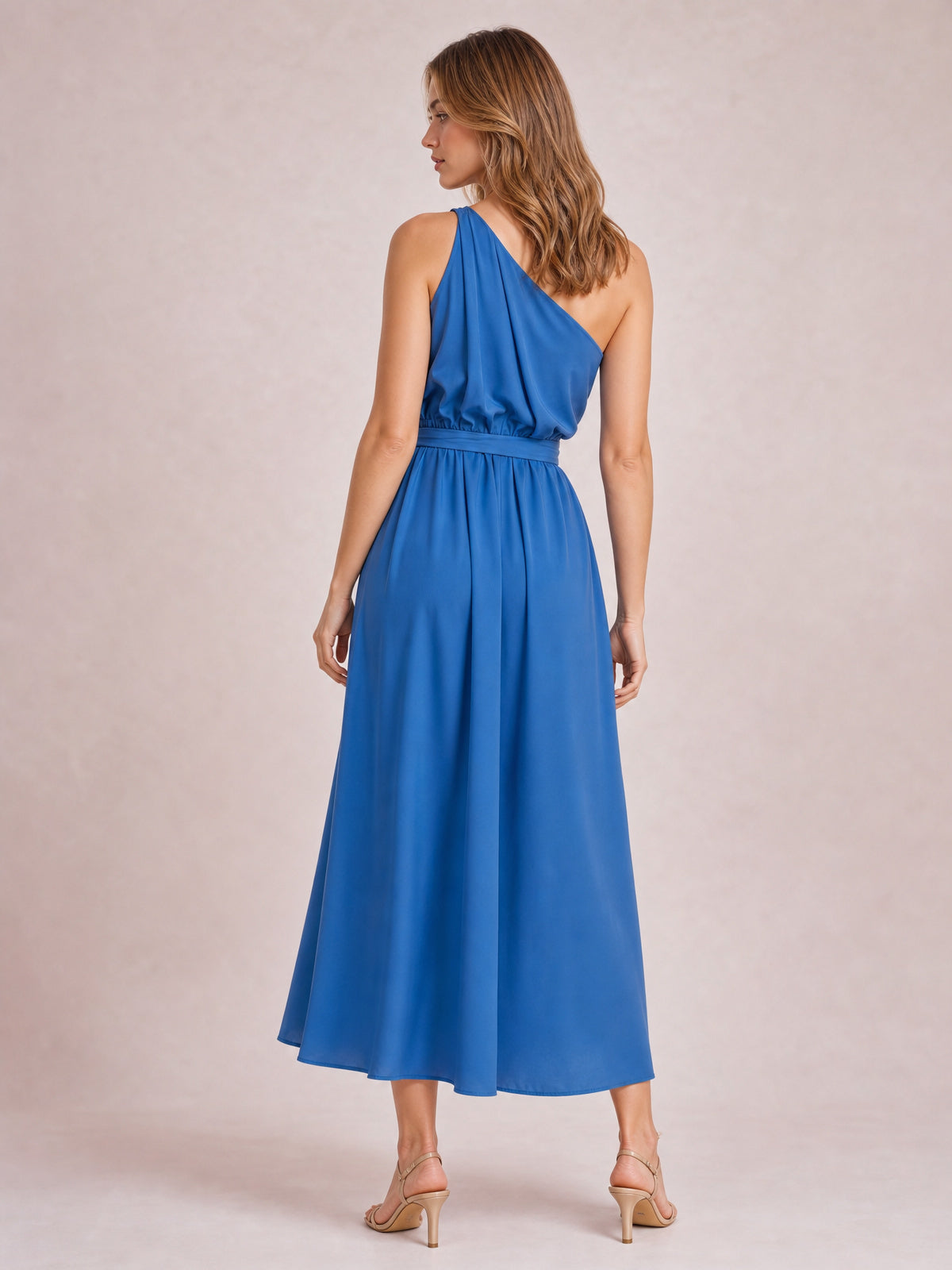 Model standing with her back turned in a blue single shoulder midi dress featuring a gathered bodice, defined waist, and flowing A-line skirt.