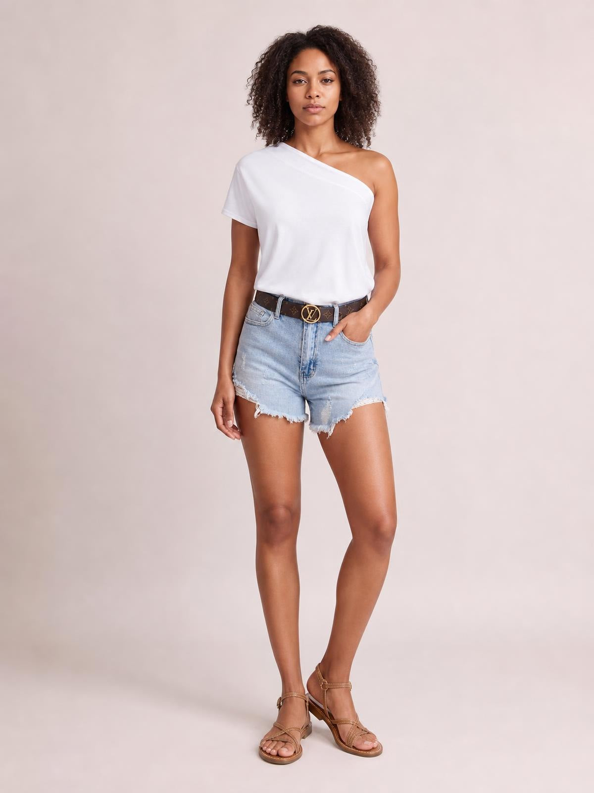 Model wears a white single-shoulder short-sleeve top with an asymmetrical neckline and relaxed silhouette, paired with distressed denim shorts.